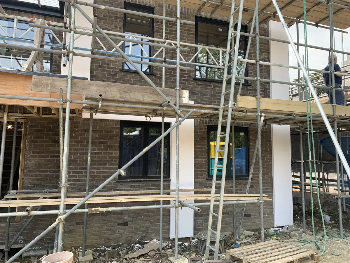 New-build houses in Brentwood under scaffolding with rendered piers between brick sections