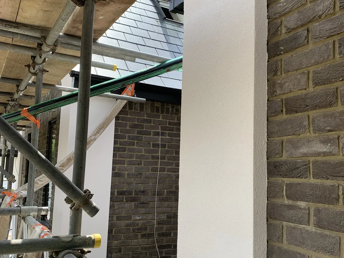 Rendered pier with a sharp beaded edge beside dark facing brickwork on a new build