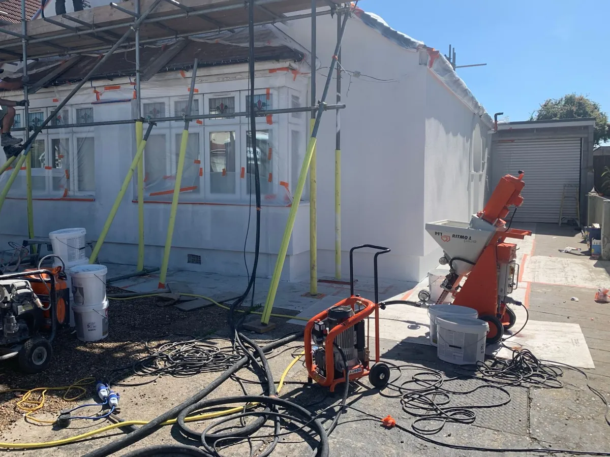 Render spraying machine on the driveway beside a Dagenham bungalow with its side wall freshly rendered in white