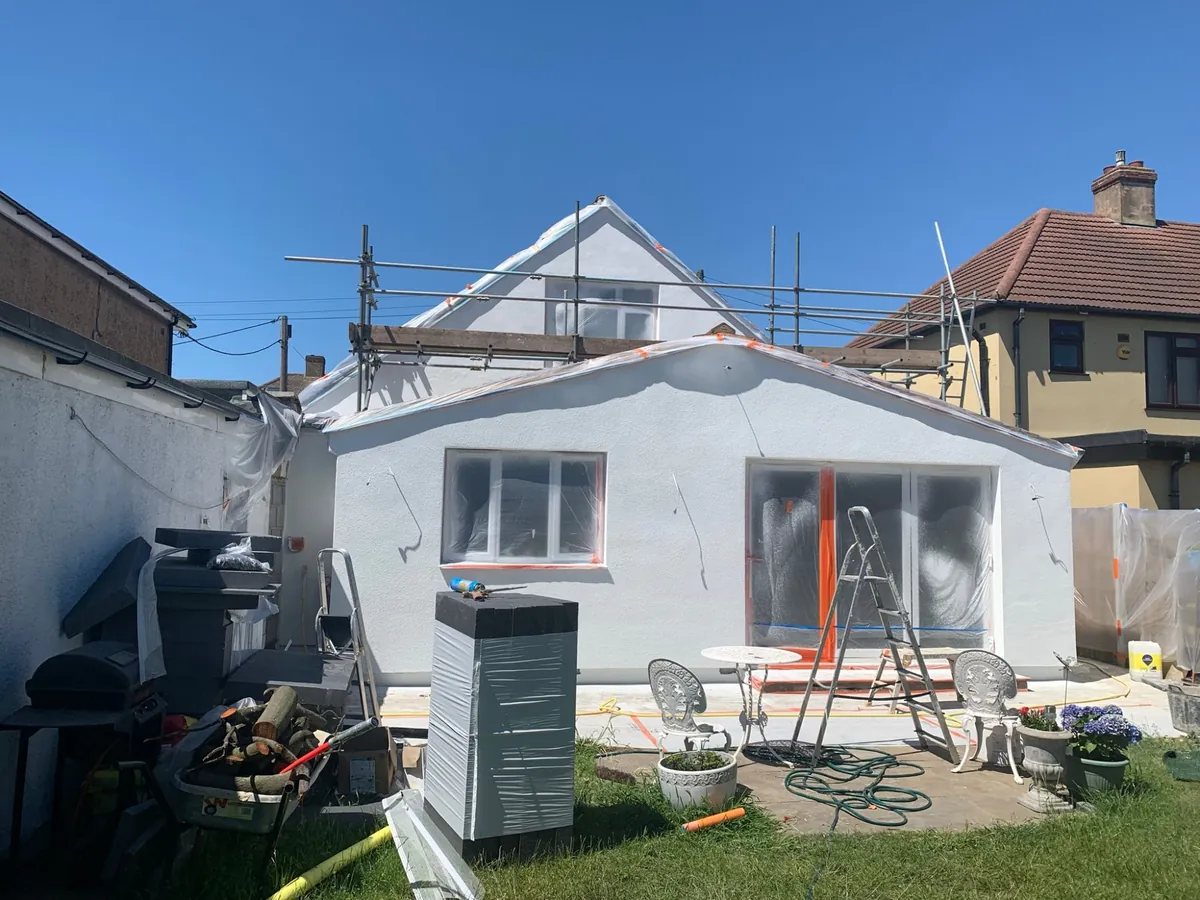 Rear of a Dagenham chalet bungalow and extension newly insulated and rendered in white, windows still masked