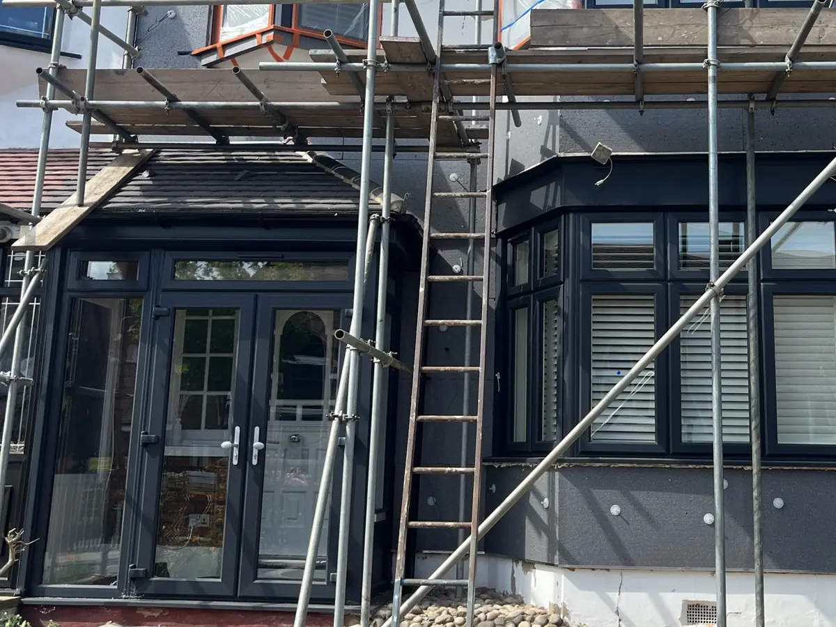 Terraced house in Ilford under scaffolding with insulation boards fixed below the bay window