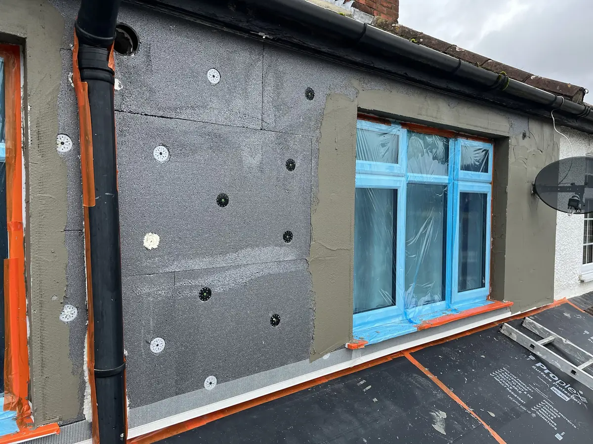 Close detail of insulation boards, fixings, reinforcing mesh and bead work around a window before the render finish is applied