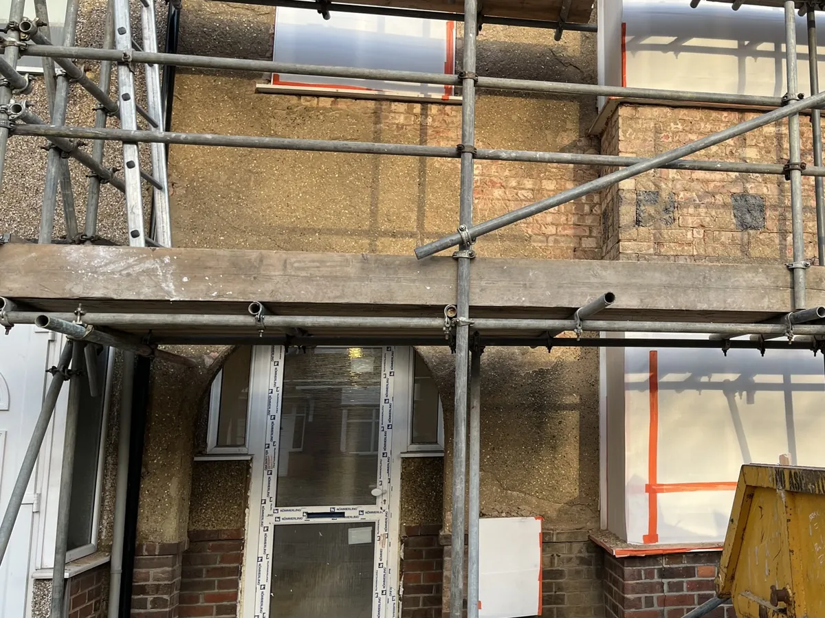 Harrow terrace under scaffolding with the old pebbledash hacked off back to brick and the windows sheeted for protection