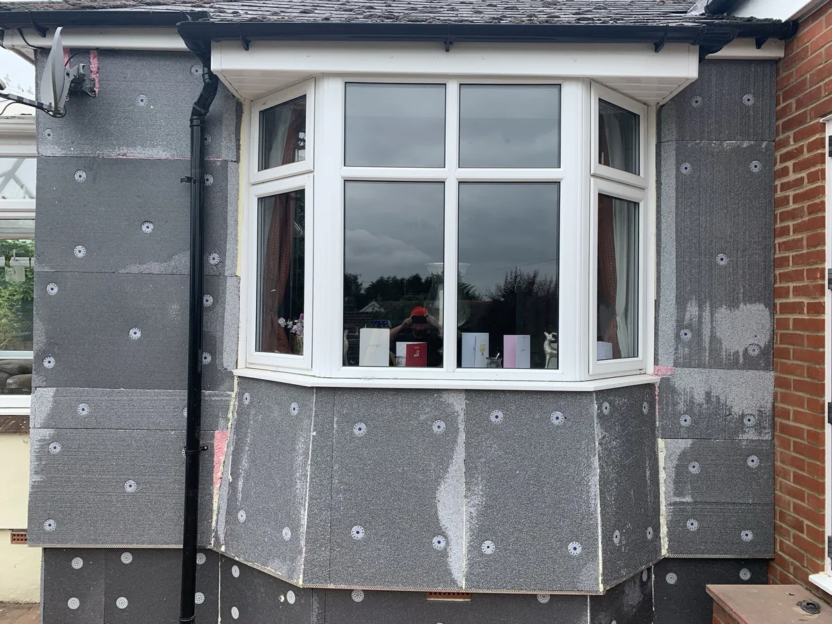 Grey insulation boards fixed round an angled bay window on a Hertfordshire bungalow