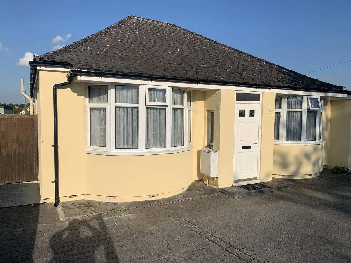 Hertfordshire bungalow finished in pale yellow render over external wall insulation, with two curved bays