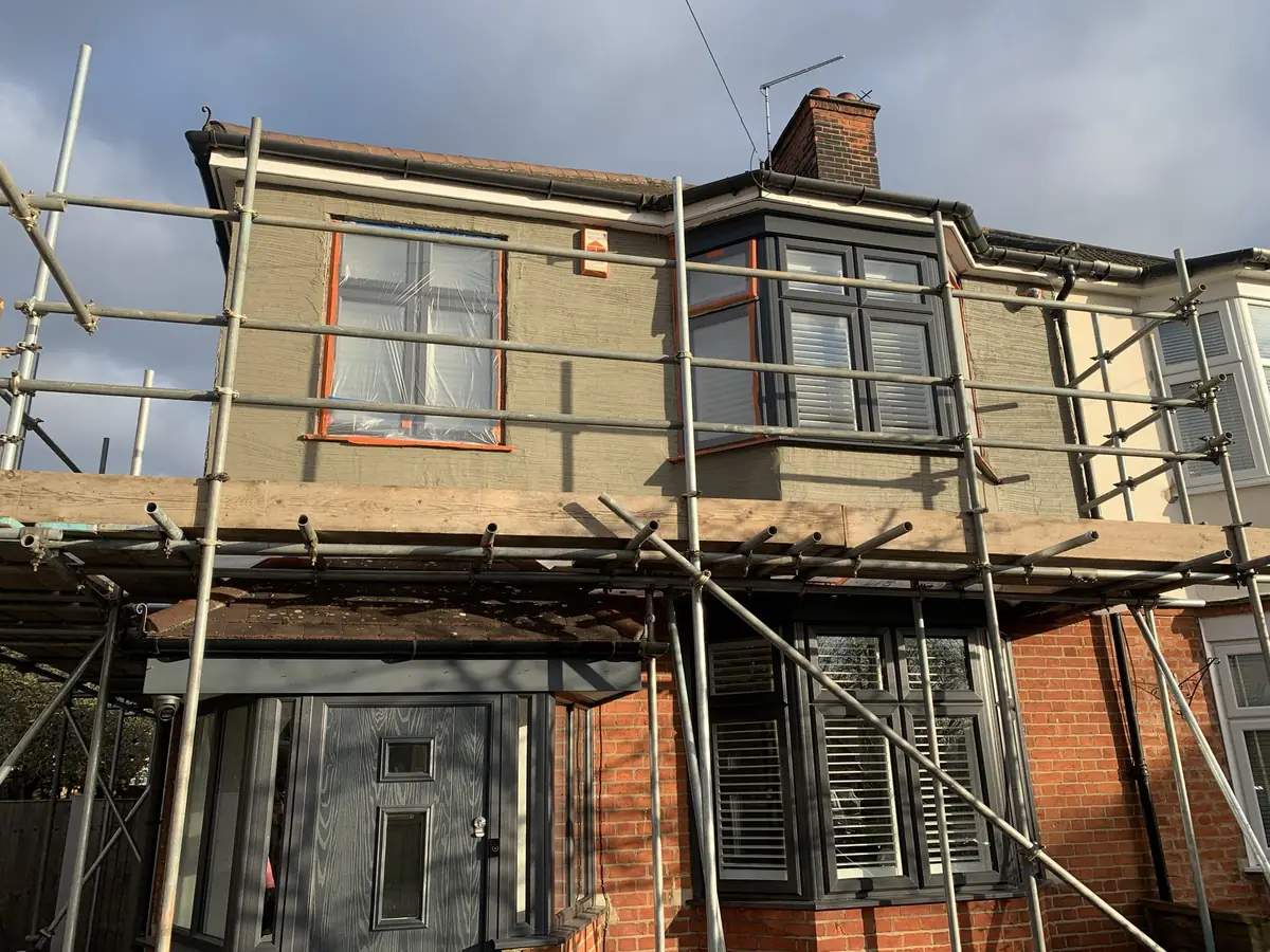 Base coat render being applied to a period semi-detached house with masked windows and bead detailing