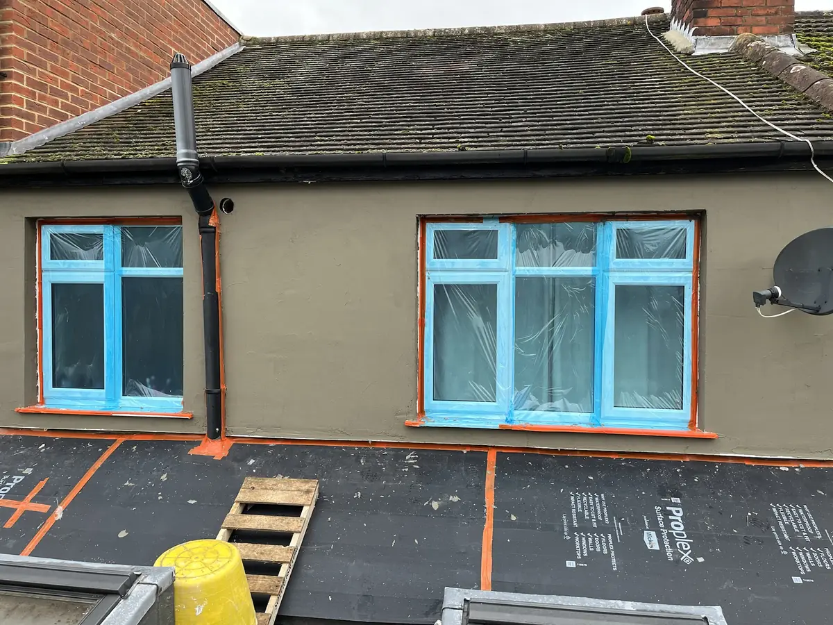 Base coat render and bead detailing being formed around windows on an older London property with surfaces masked and protected