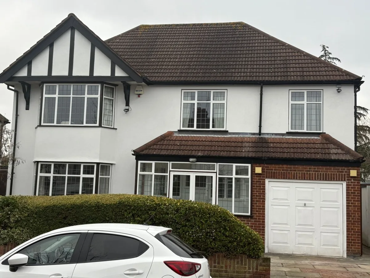 Front of the same detached house finished in white render with black timber detailing on the gable