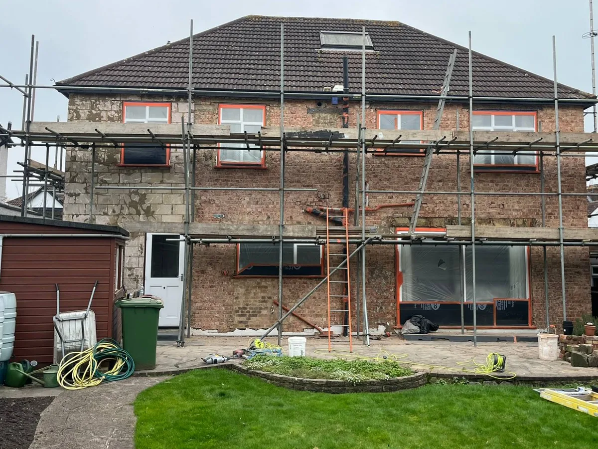 Rear of a detached London house under scaffolding with the old render removed back to the brickwork