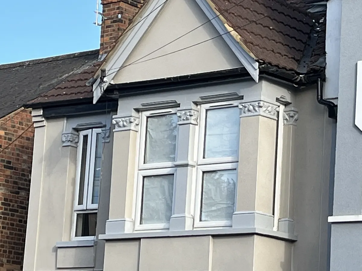 The same period bay after render repair with a smooth new finish and restored window details