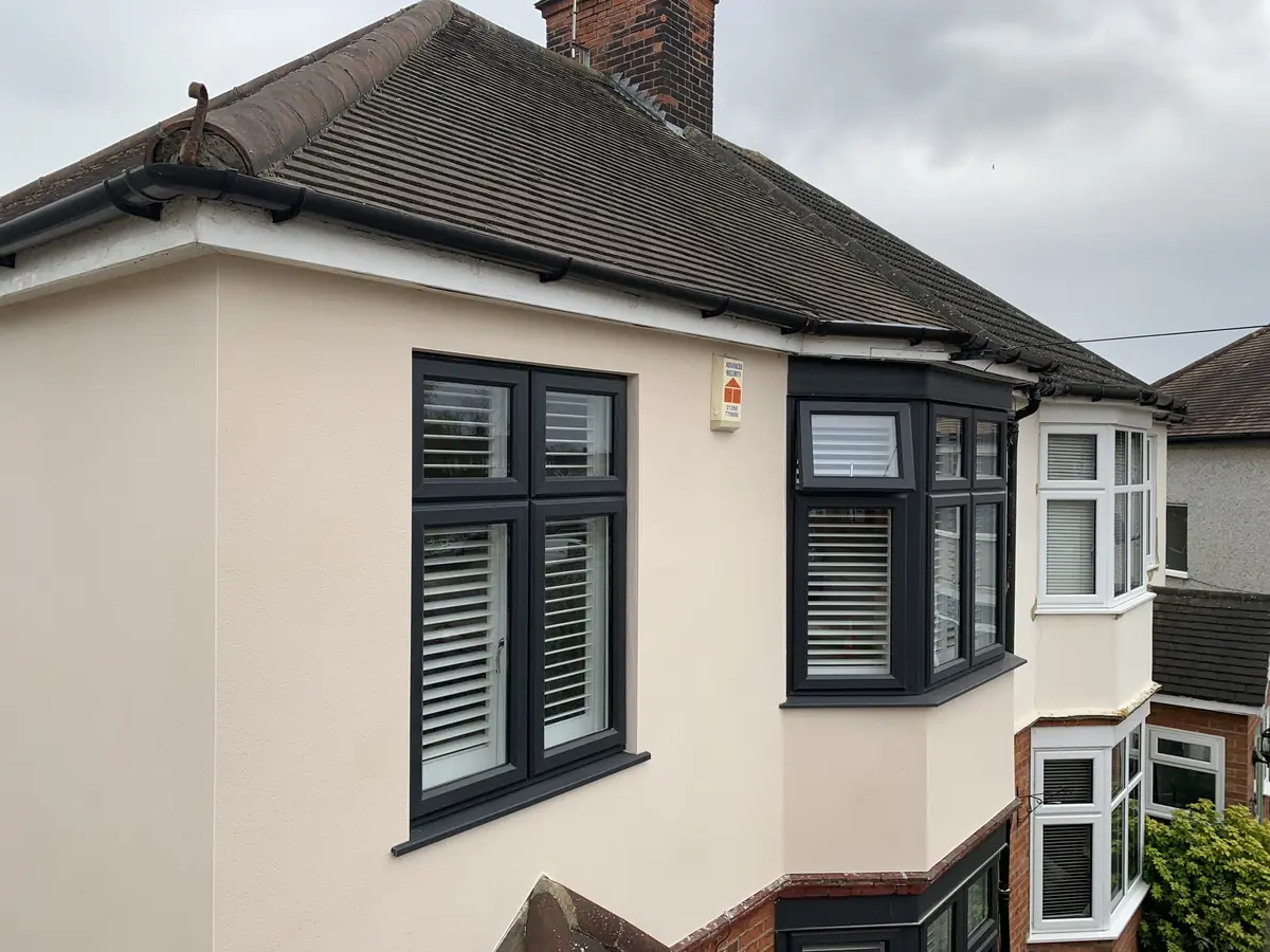 Close view of a completed thin-coat render finish around a bay window on a period London home