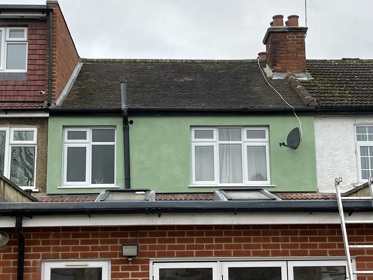 Rendered rear elevation of a London home in a green through-coloured finish, next to a neighbouring property in original pebbledash