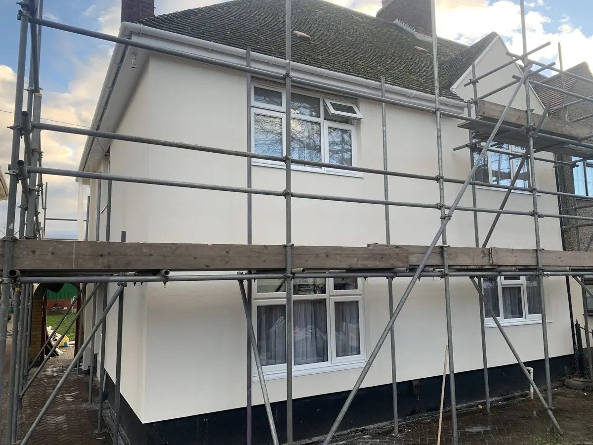Completed white render finish on an interwar semi-detached house with scaffolding still in place