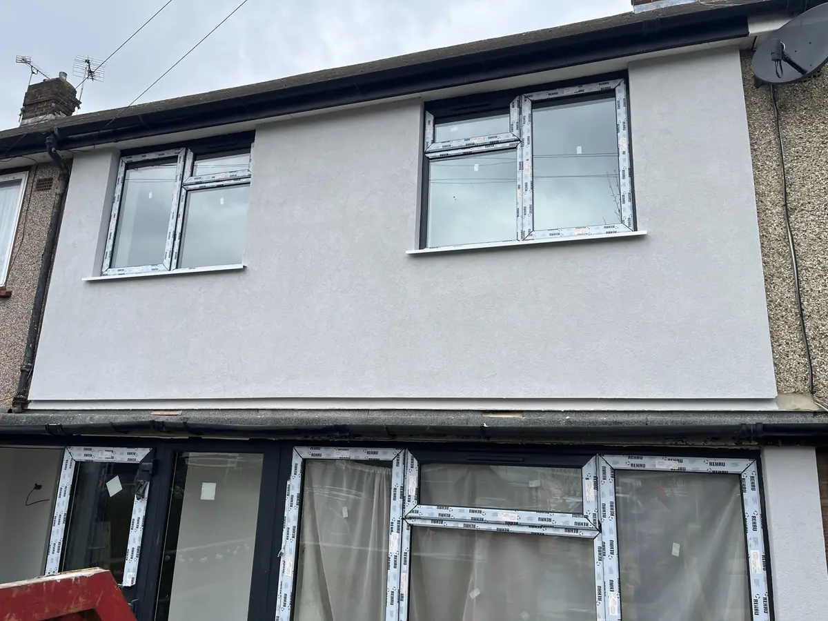 Completed render finish on a London terrace next to a neighbouring property in original pebbledash