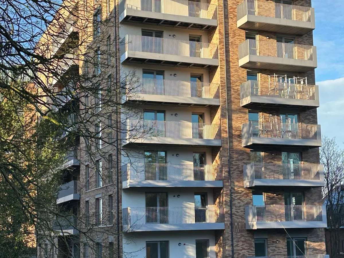 New-build block of flats in West London with rendered recessed balcony walls between brick sections